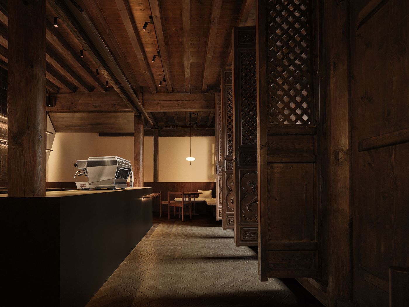 A modern coffee shop interior featuring a sleek espresso machine, wooden beams, intricate wooden partitions, and warm lighting. A modern coffee shop interior featuring a sleek espresso machine, wooden beams, intricate wooden partitions, and warm lighting.