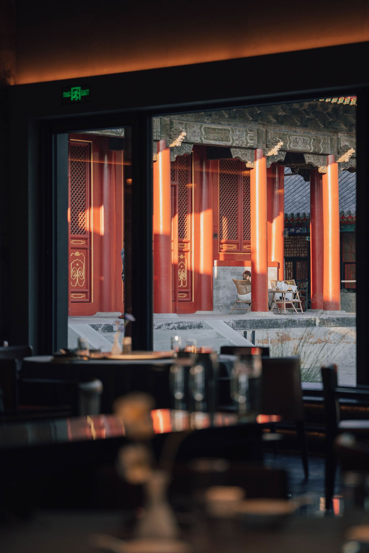 View through a large window showcasing a traditional red pavilion with intricate details, surrounded by a peaceful outdoor setting. View through a large window showcasing a traditional red pavilion with intricate details, surrounded by a peaceful outdoor setting.