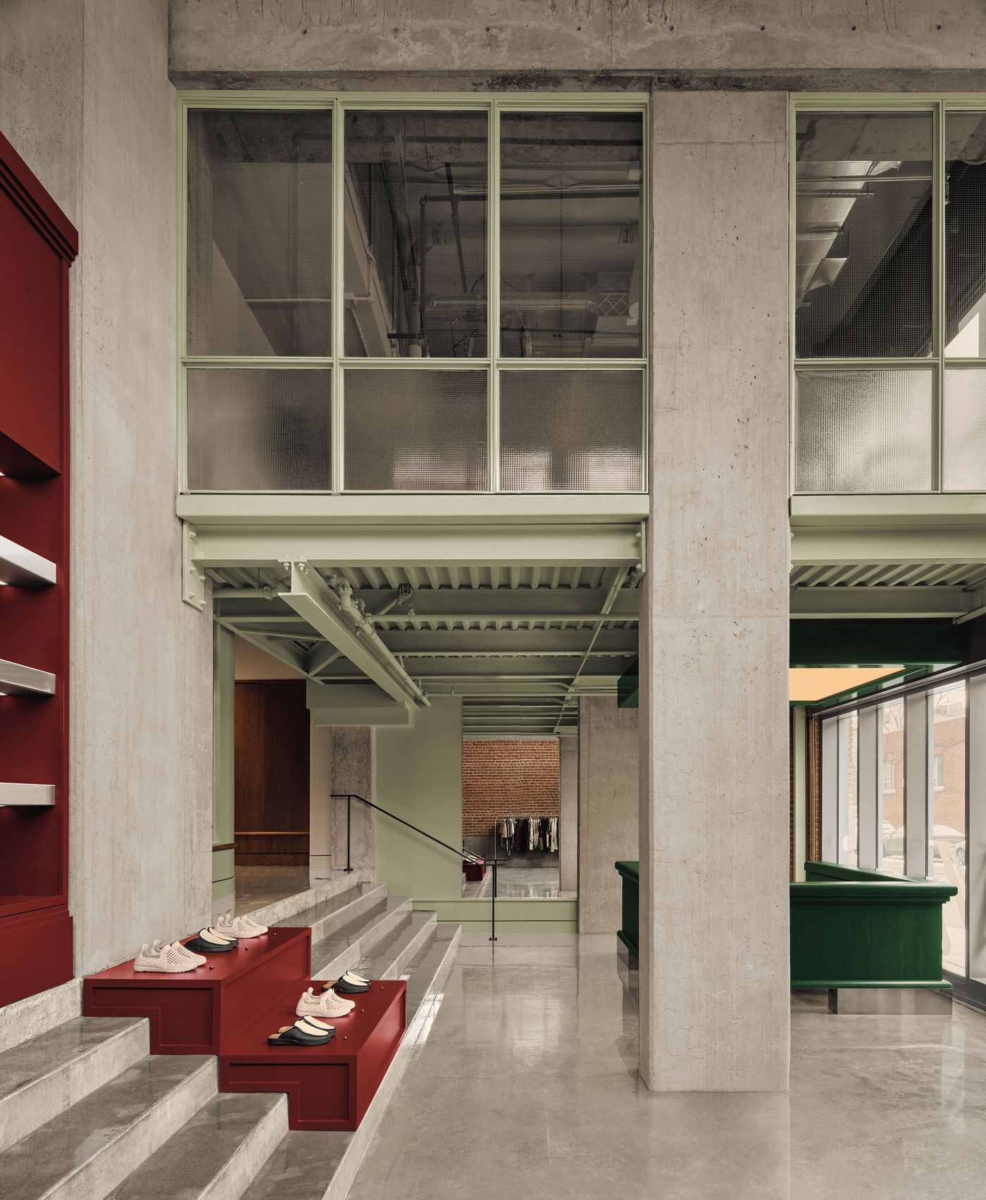 Modern retail space featuring concrete and green accents, with red display steps showcasing shoes and a stylish, open layout. Modern retail space featuring concrete and green accents, with red display steps showcasing shoes and a stylish, open layout.