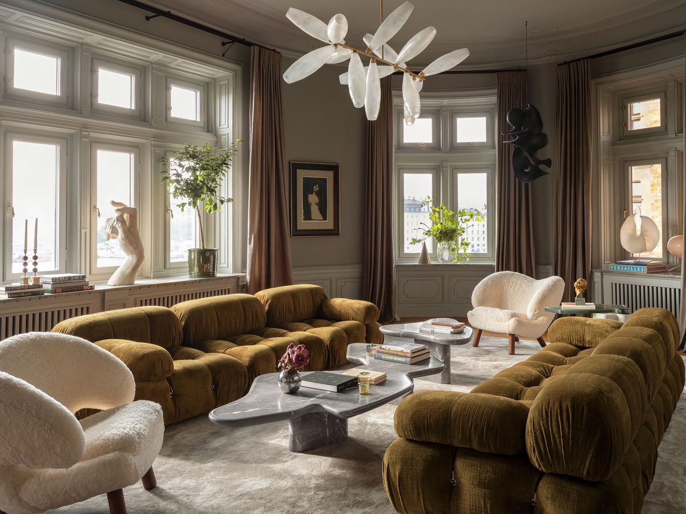 A stylish, modern living room featuring plush brown sofas, cozy white chairs, large windows, art, and elegant decor. A stylish, modern living room featuring plush brown sofas, cozy white chairs, large windows, art, and elegant decor.
