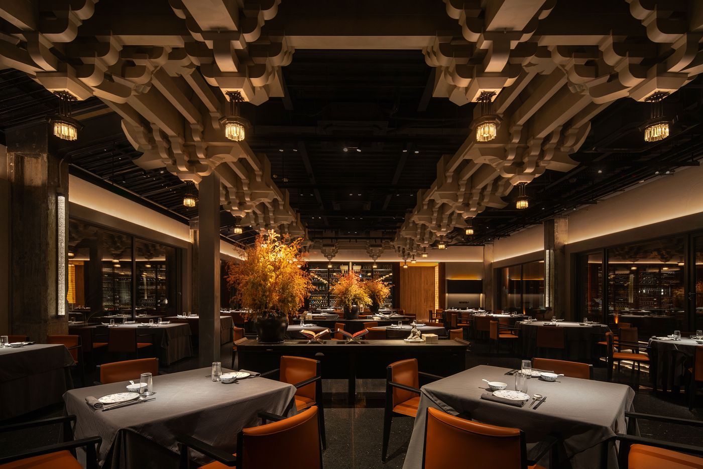 Elegant restaurant interior featuring modern decor, dramatic lighting, and tables adorned with dark linens and decorative centerpieces. Elegant restaurant interior featuring modern decor, dramatic lighting, and tables adorned with dark linens and decorative centerpieces.