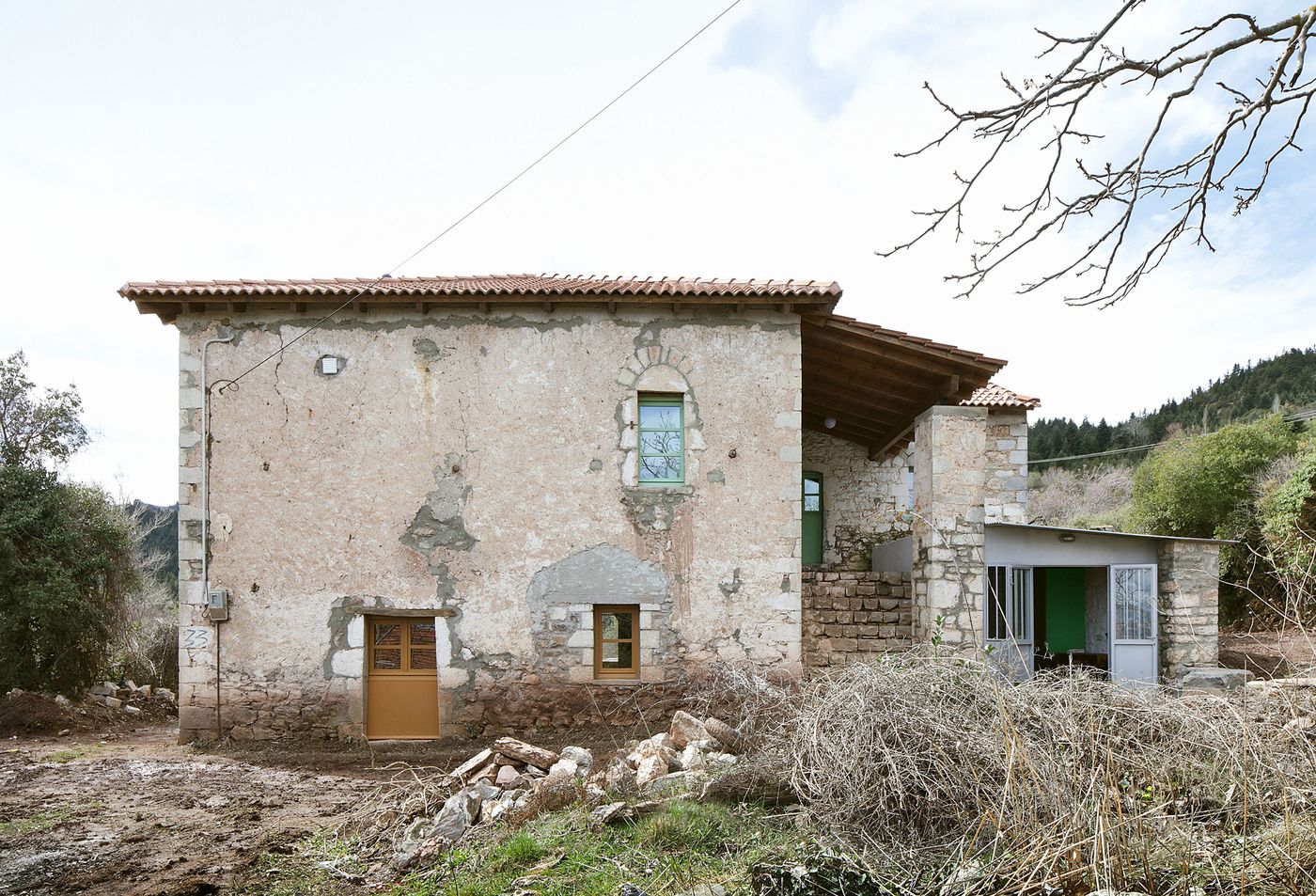 A weathered stone facade displays centuries of patina and repair, creating an authentic textural narrative. The deteriorated plaster and exposed stonework reveal the building's temporal layers, while modern apertures introduce carefully considered contemporary elements into this historical fabric.