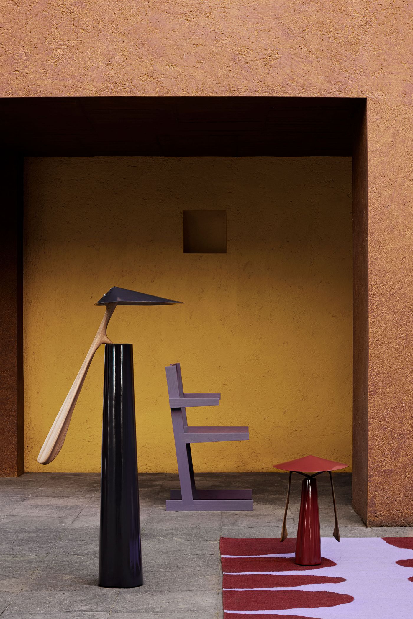 A vibrant scene featuring colorful modern furniture: a black lamp, a purple chair, and a red table, against a warm yellow and orange backdrop.