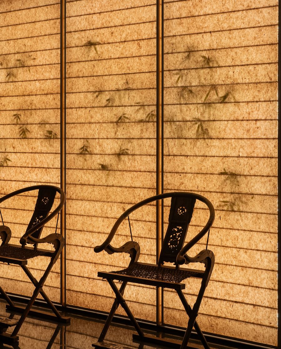 Two elegant black chairs are positioned beside translucent, textured screens resembling soft fabric with faint bamboo patterns. Two elegant black chairs are positioned beside translucent, textured screens resembling soft fabric with faint bamboo patterns.