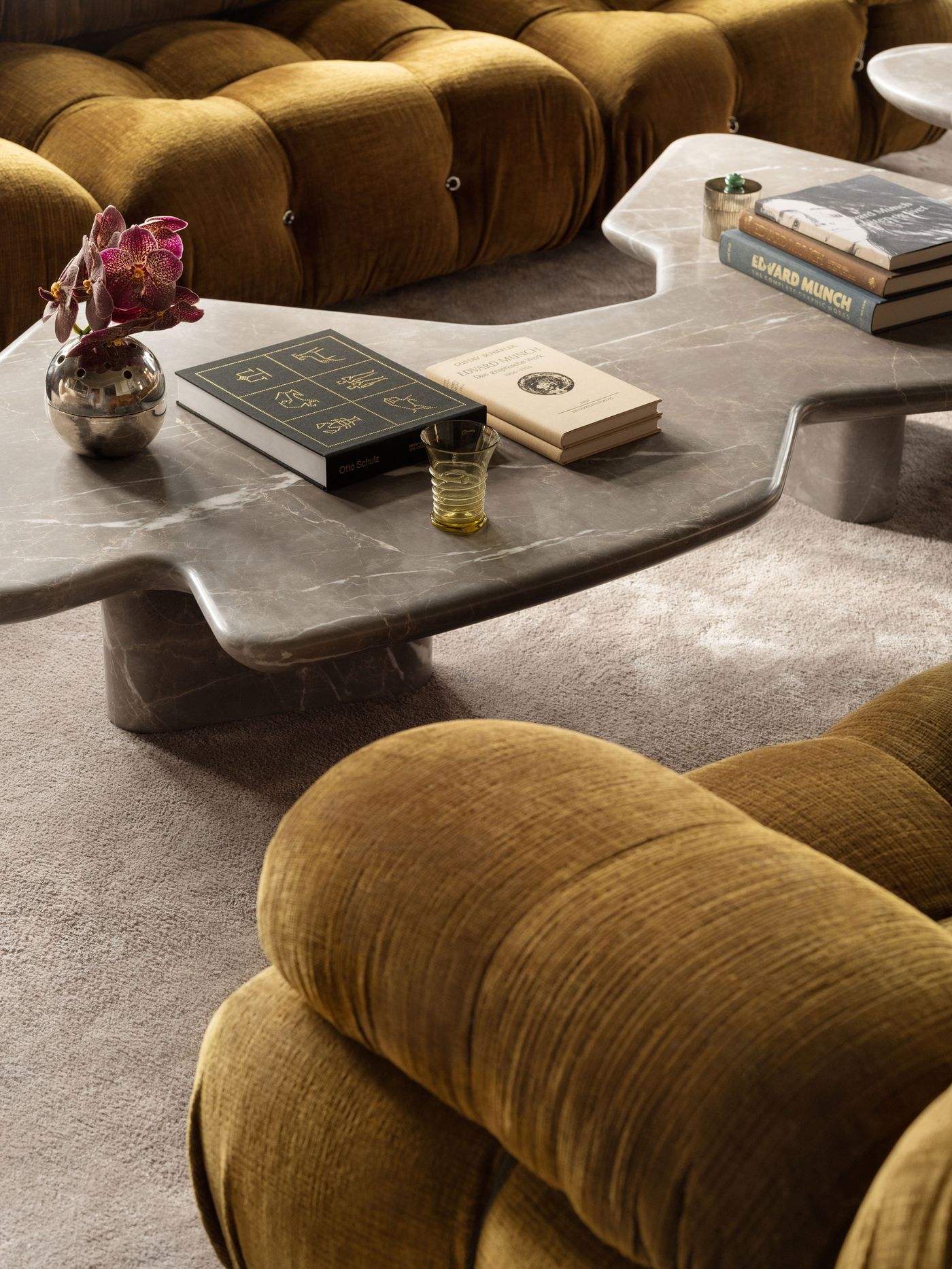 A cozy living room featuring a modern marble coffee table adorned with books and a flower vase beside plush mustard-colored sofas. A cozy living room featuring a modern marble coffee table adorned with books and a flower vase beside plush mustard-colored sofas.