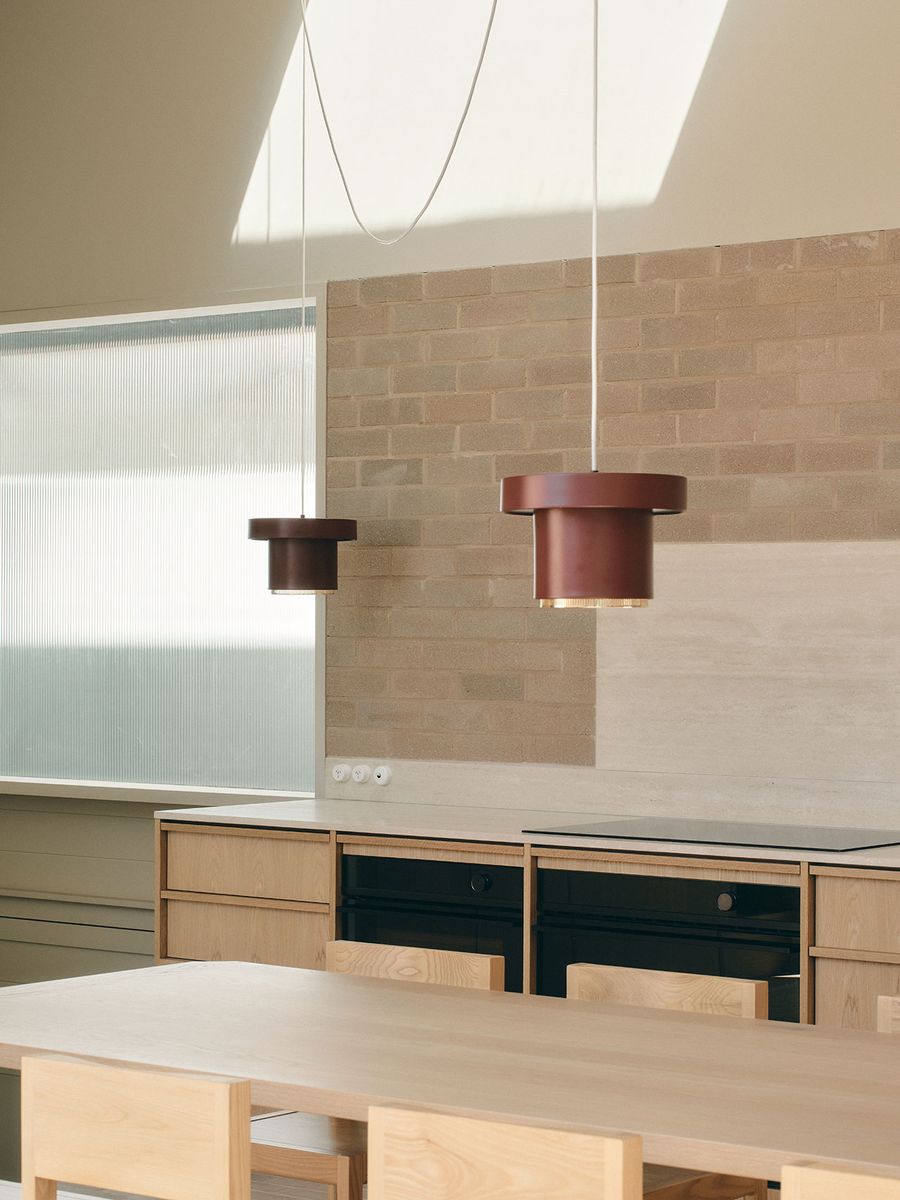 Modern kitchen interior featuring two stylish pendant lights, wooden cabinetry, and a textured brick backdrop, illuminated by natural light. Modern kitchen interior featuring two stylish pendant lights, wooden cabinetry, and a textured brick backdrop, illuminated by natural light.