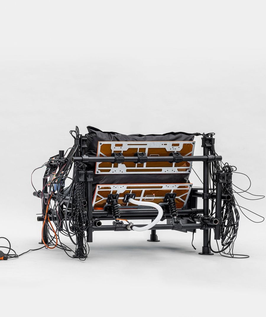 A complex, industrial-style assembly with exposed wires, components, and a black structure, resembling a high-tech seating system. A complex, industrial-style assembly with exposed wires, components, and a black structure, resembling a high-tech seating system.