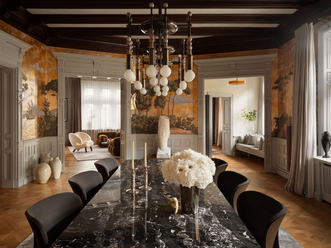 Elegant dining room featuring a marble table, floral centerpiece, vintage decor, and soft lighting accentuated by artistic wall murals. Elegant dining room featuring a marble table, floral centerpiece, vintage decor, and soft lighting accentuated by artistic wall murals.