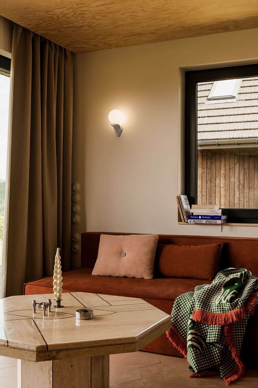 Eclectic interior featuring a brown sofa, decorative pillows, a marble hexagonal table, and a warm light fixture by the window. Eclectic interior featuring a brown sofa, decorative pillows, a marble hexagonal table, and a warm light fixture by the window.
