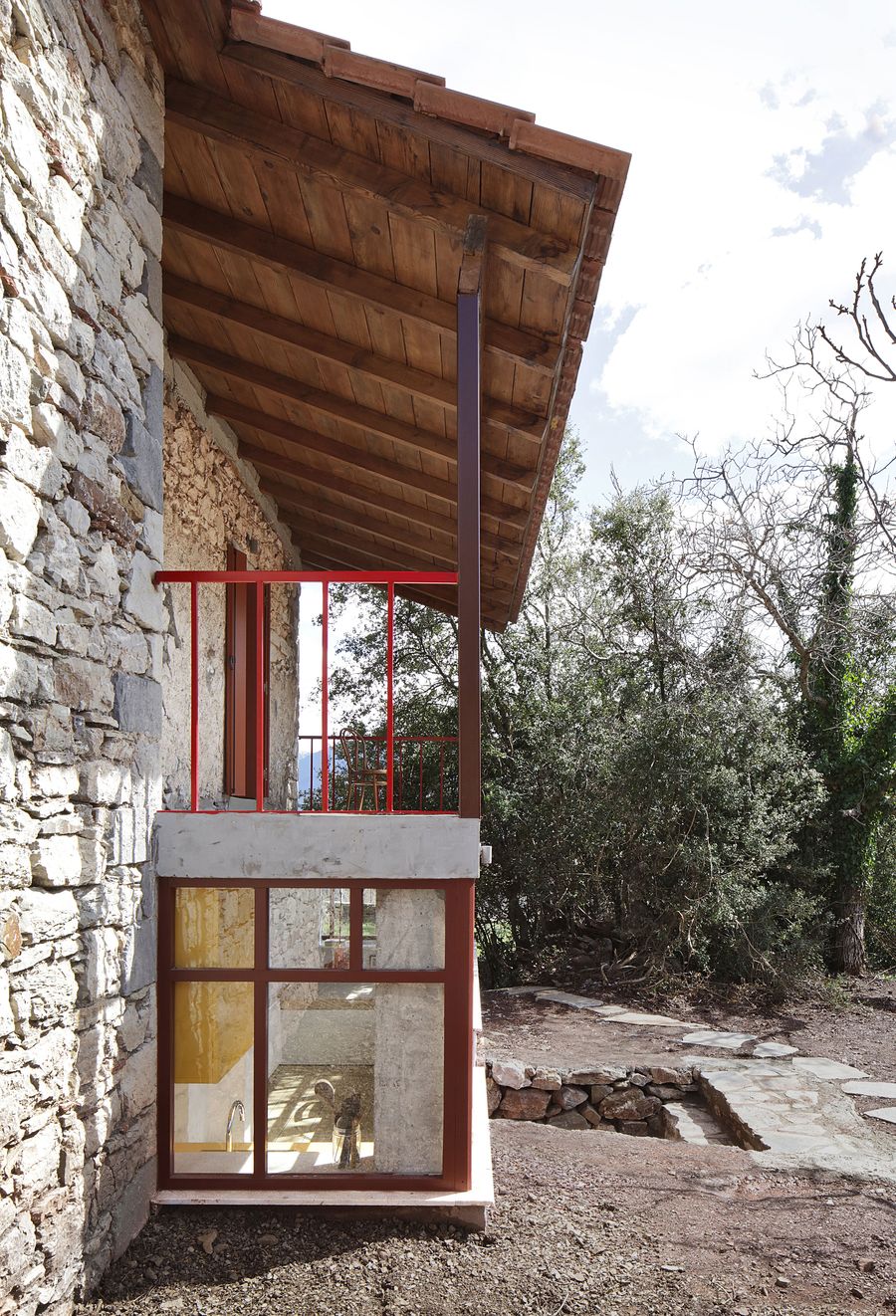 Exposed timber roof structure reveals traditional construction methods beneath contemporary clay tiles. The wooden beam ceiling creates intimate scale while the coral-red steel balustrade provides modern safety requirements, illustrating the project's dialogue between old and new.