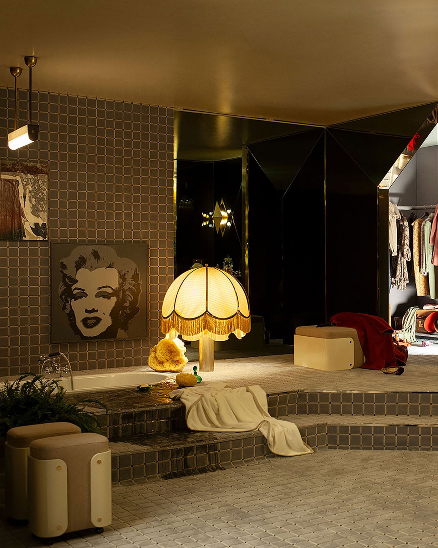 A stylish bathroom featuring a vintage lamp, Pop Art artwork, plush seating, a cozy blanket, and a reflection of clothing in a glossy background.