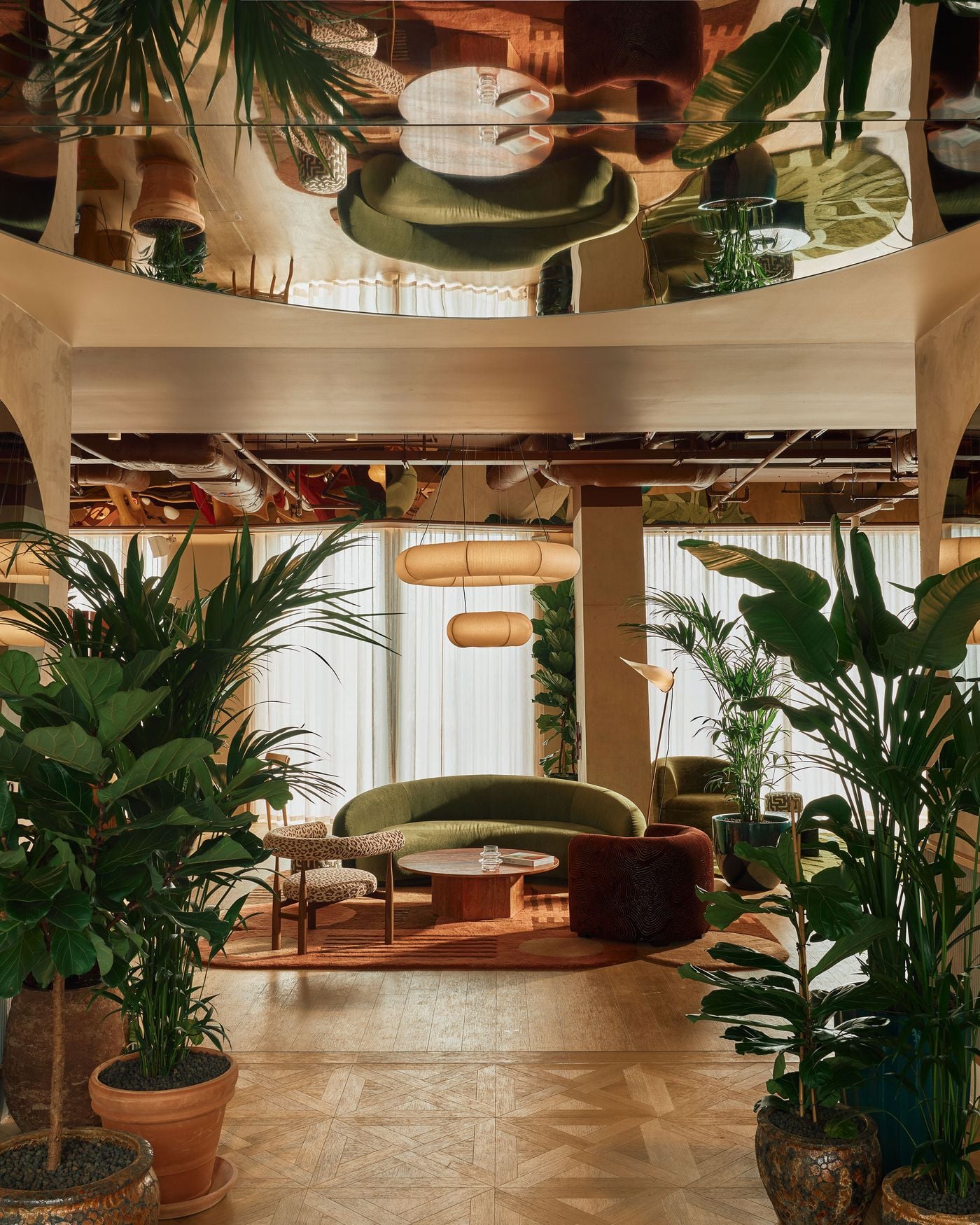 Lush planting frames the entrance lounge at Locke London Canary Wharf, where Holloway Li layers curved mid-century seating, patterned rugs and warm timber beneath a mirrored ceiling. The reflective surface doubles the greenery and furnishings overhead, lending the relaxed, biophilic setting an unexpected sense of theatricality. Lush planting frames the entrance lounge at Locke London Canary Wharf, where Holloway Li layers curved mid-century seating, patterned rugs and warm timber beneath a mirrored ceiling. The reflective surface doubles the greenery and furnishings overhead, lending the relaxed, biophilic setting an unexpected sense of theatricality.