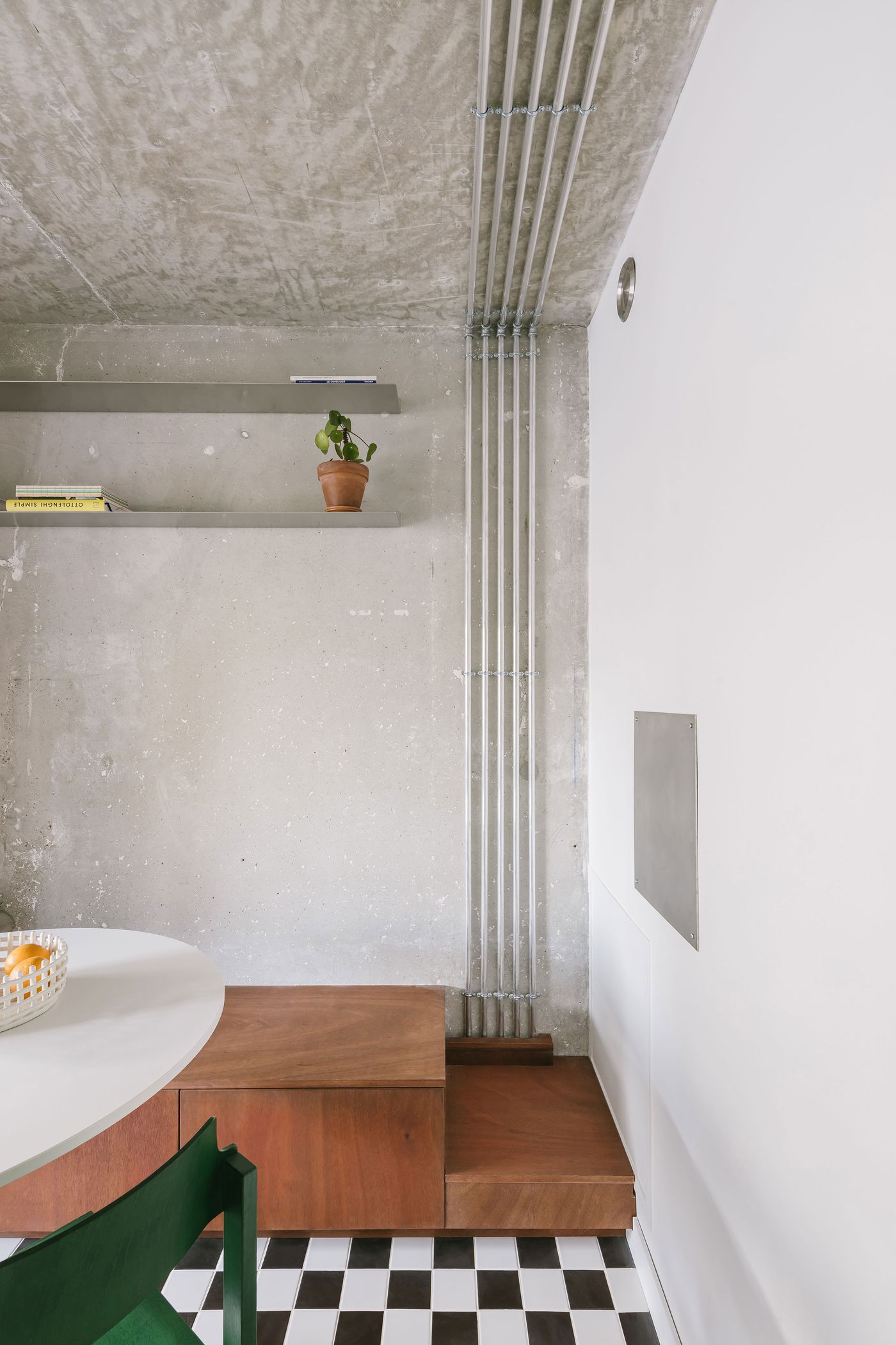 Modern interior featuring a minimalist design with concrete walls, wooden furniture, green plant, and contrasting black-and-white flooring. Modern interior featuring a minimalist design with concrete walls, wooden furniture, green plant, and contrasting black-and-white flooring.