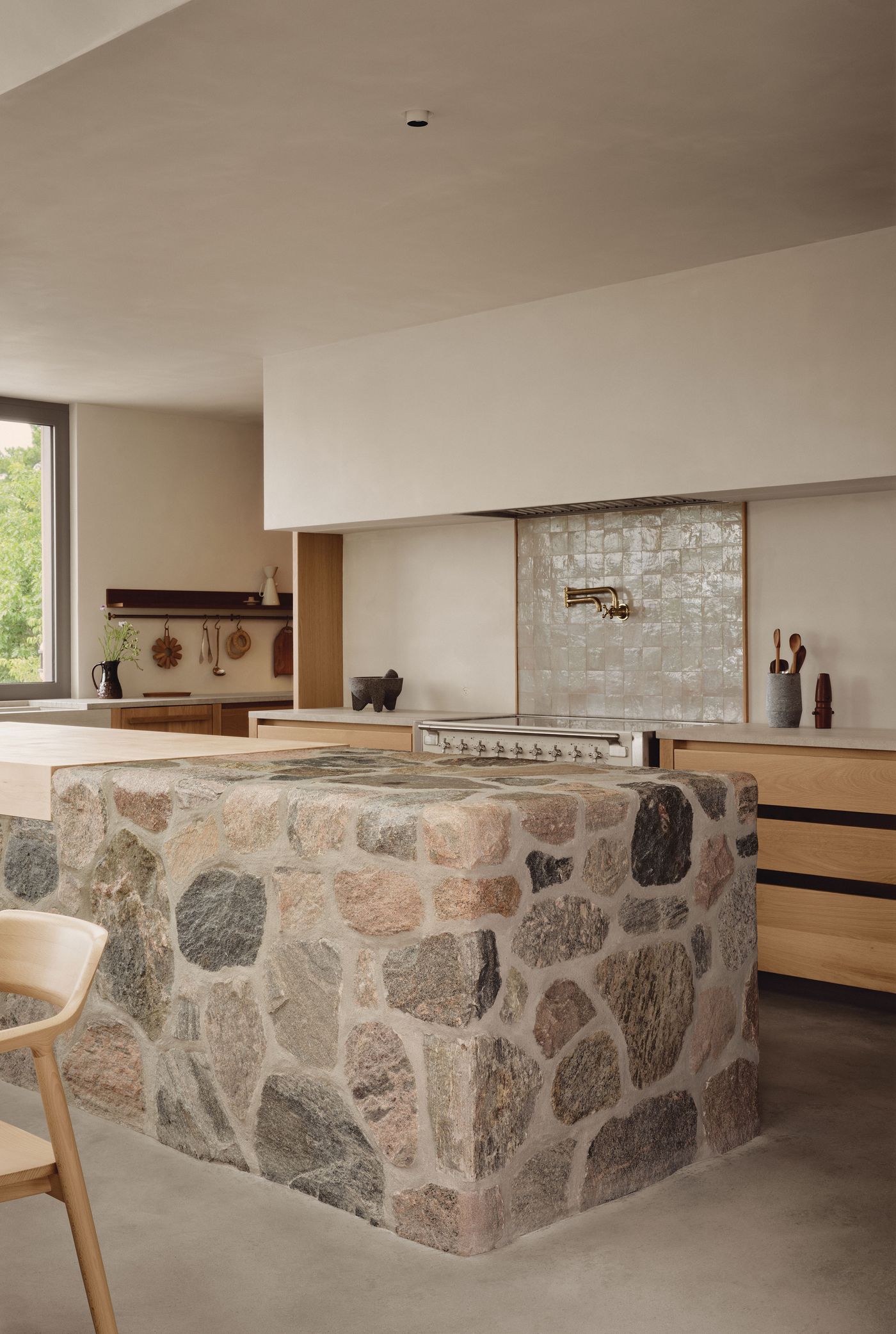 Modern kitchen featuring a stone island, wooden cabinets, and a contemporary cooking area with minimalist decor and natural light. Modern kitchen featuring a stone island, wooden cabinets, and a contemporary cooking area with minimalist decor and natural light.
