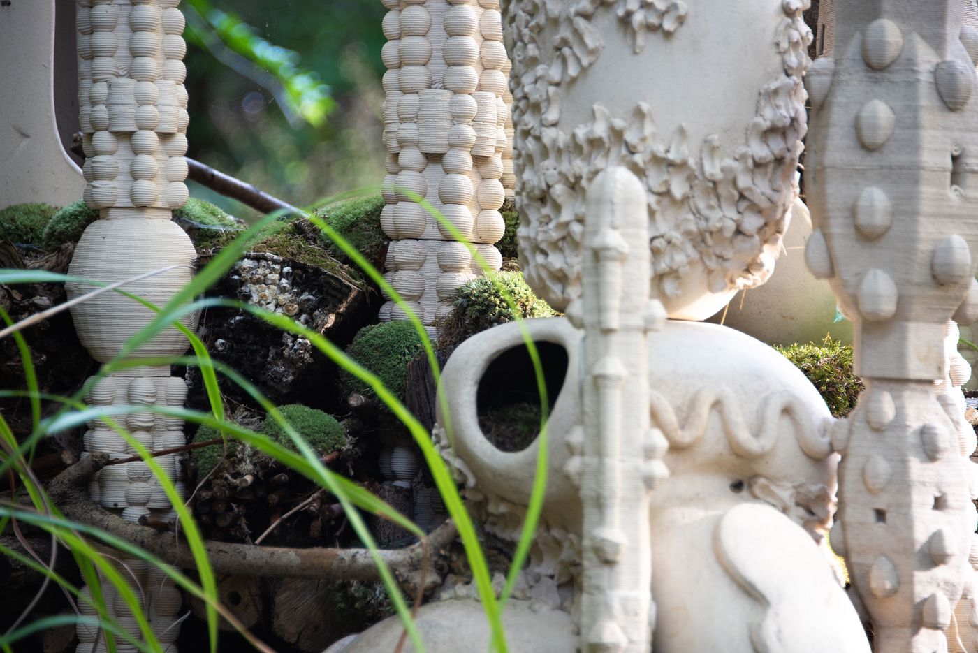 A close-up of artistic ceramic sculptures with varied textures, surrounded by moss and greenery, creating a natural, whimsical atmosphere. A close-up of artistic ceramic sculptures with varied textures, surrounded by moss and greenery, creating a natural, whimsical atmosphere.