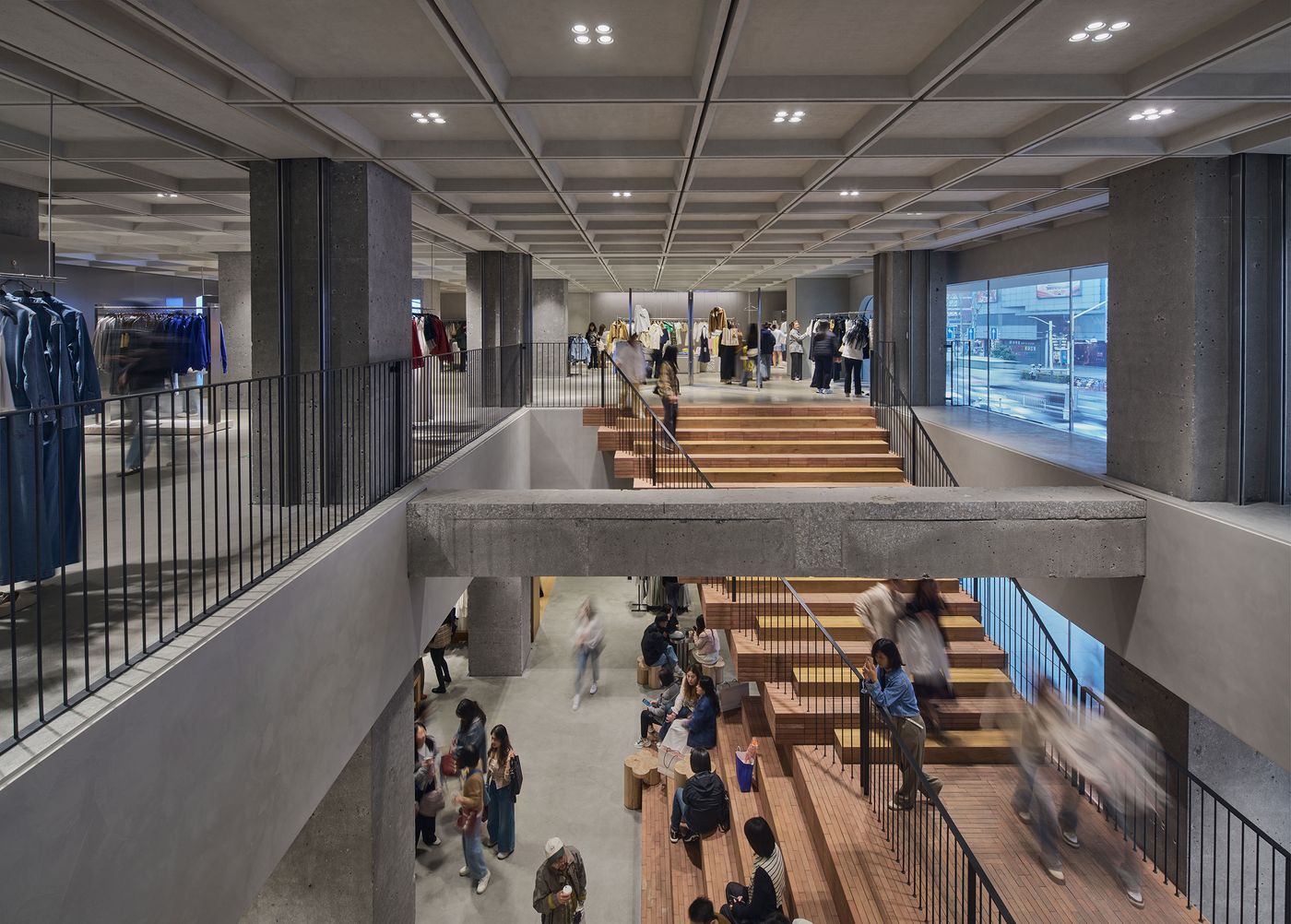 A modern retail space with brick stairs and concrete columns, bustling with shoppers and colorful clothing displays. A modern retail space with brick stairs and concrete columns, bustling with shoppers and colorful clothing displays.