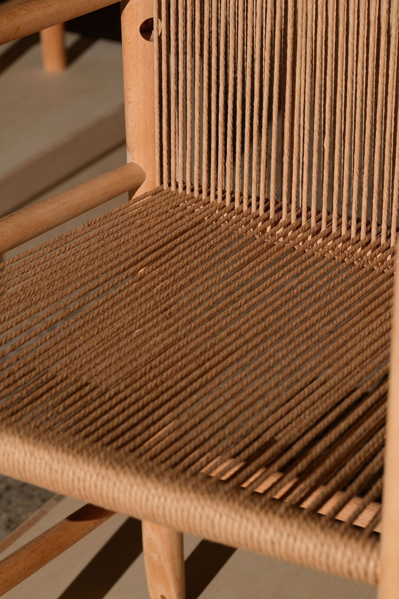 Close-up of a minimalist wooden chair with woven rope seat, showcasing intricate patterns and natural textures in warm, soft lighting. Close-up of a minimalist wooden chair with woven rope seat, showcasing intricate patterns and natural textures in warm, soft lighting.