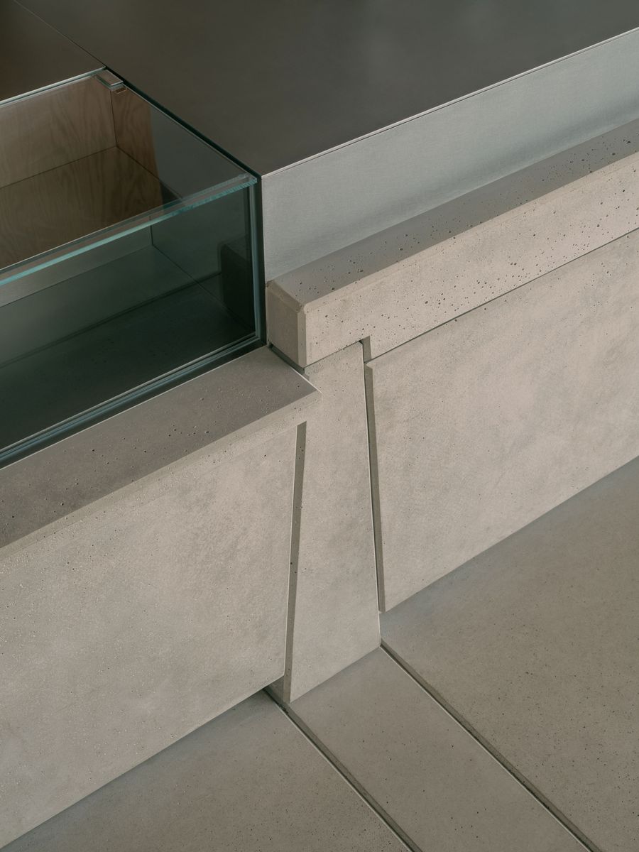 A close-up of the café’s concrete counter reveals precise geometric joinery and crisp detailing, where brushed steel, exposed aggregate concrete, and low-iron glass intersect with quiet elegance—illustrating Atelier TAO+C’s refined industrial minimalism.
