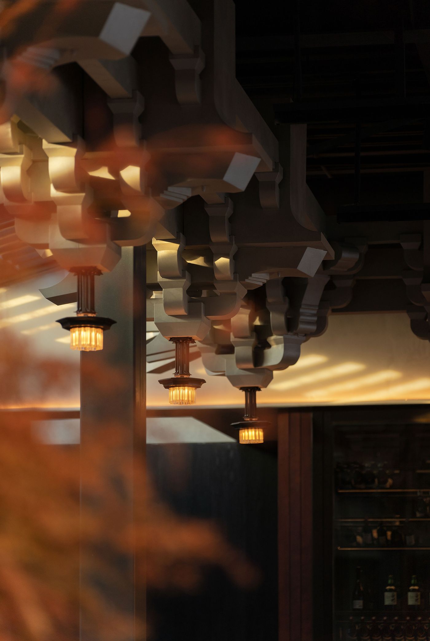 Intricate architectural details with warm pendant lights suspended from an elegant ceiling, creating a cozy ambiance.