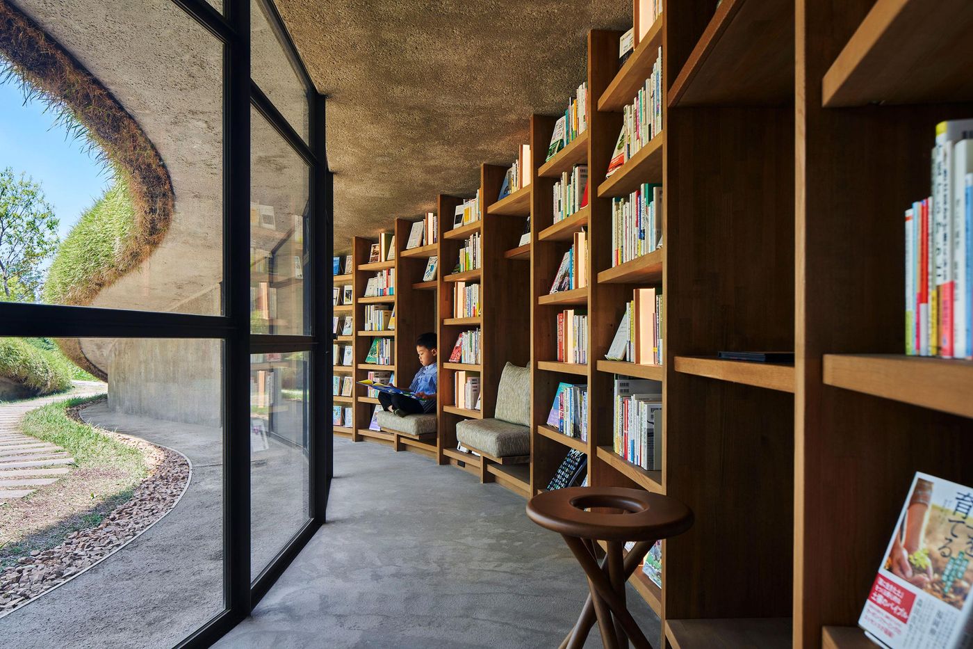 A cozy reading nook featuring wooden bookshelves filled with books, a comfortable chair, and large glass windows illuminating the space. A cozy reading nook featuring wooden bookshelves filled with books, a comfortable chair, and large glass windows illuminating the space.