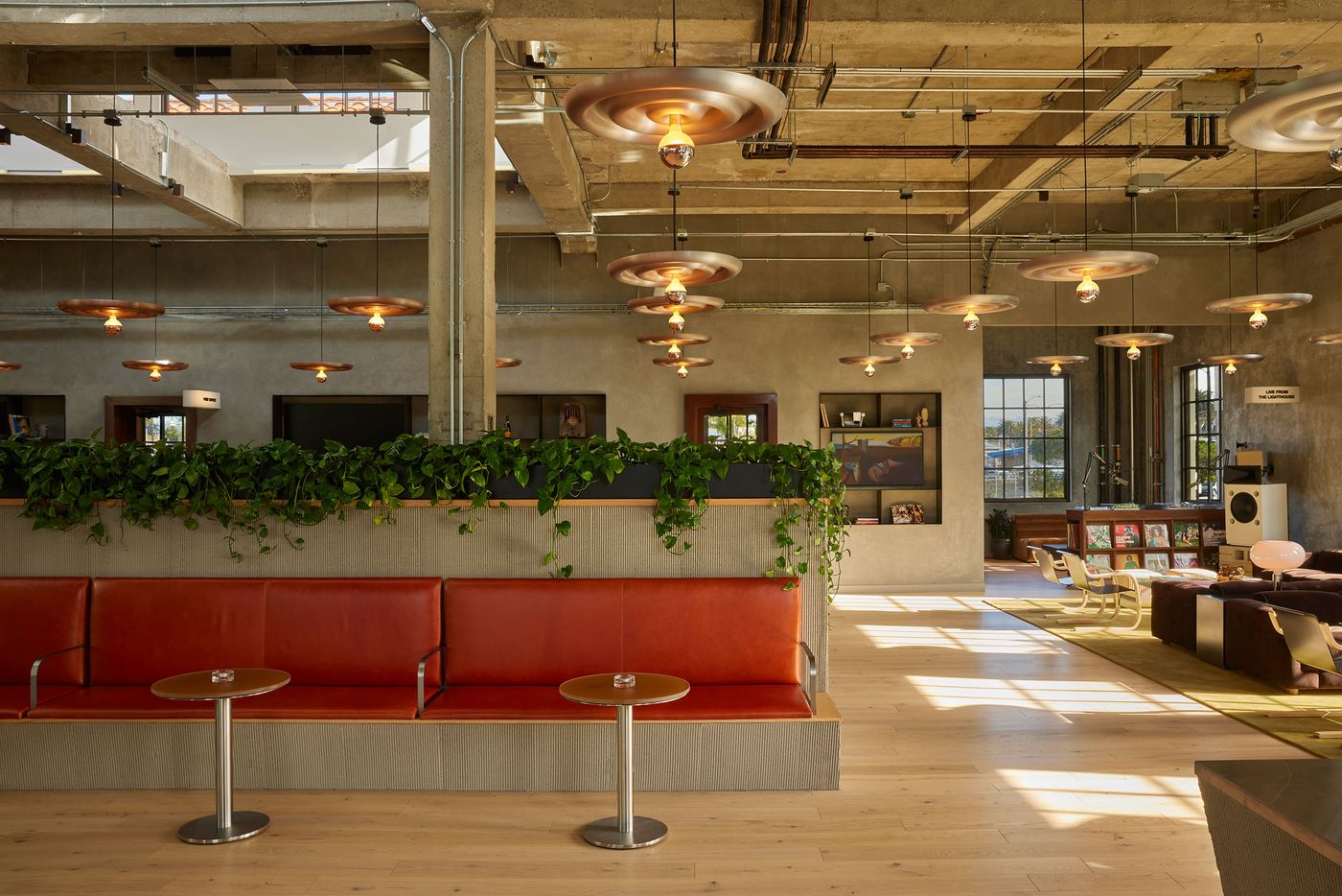 A stylish lounge featuring orange seating, modern pendant lights, and greenery against a backdrop of industrial decor and natural light. A stylish lounge featuring orange seating, modern pendant lights, and greenery against a backdrop of industrial decor and natural light.