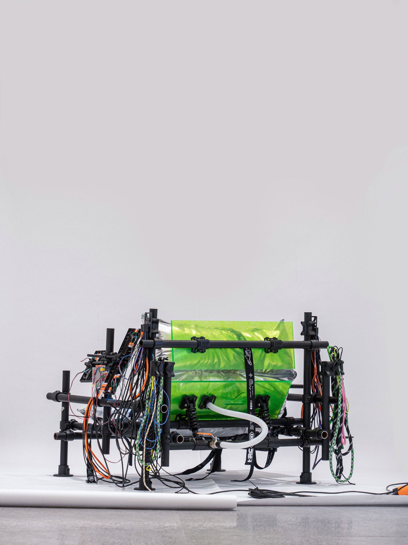 A modern, industrial-style chair with metallic cushions and colorful cables, showcasing an innovative design in a minimalist setting. A modern, industrial-style chair with metallic cushions and colorful cables, showcasing an innovative design in a minimalist setting.