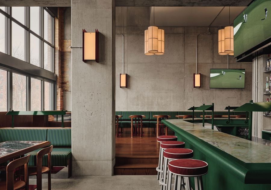 Modern bar interior with green accents, wooden furniture, large windows, and pendant lighting, featuring a TV and marble countertop.