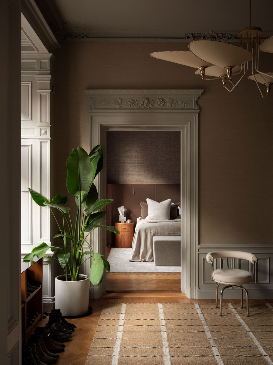 A cozy bedroom view through an elegant doorway, featuring a plant, minimalist decor, and warm wood accents. Soft lighting enhances the ambiance. A cozy bedroom view through an elegant doorway, featuring a plant, minimalist decor, and warm wood accents. Soft lighting enhances the ambiance.