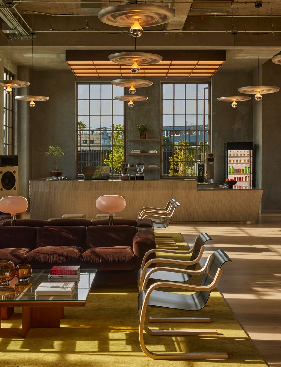 A stylish lounge with a brown sofa, elegant chairs, and unique light fixtures, featuring large windows and a vibrant yellow carpet. A stylish lounge with a brown sofa, elegant chairs, and unique light fixtures, featuring large windows and a vibrant yellow carpet.