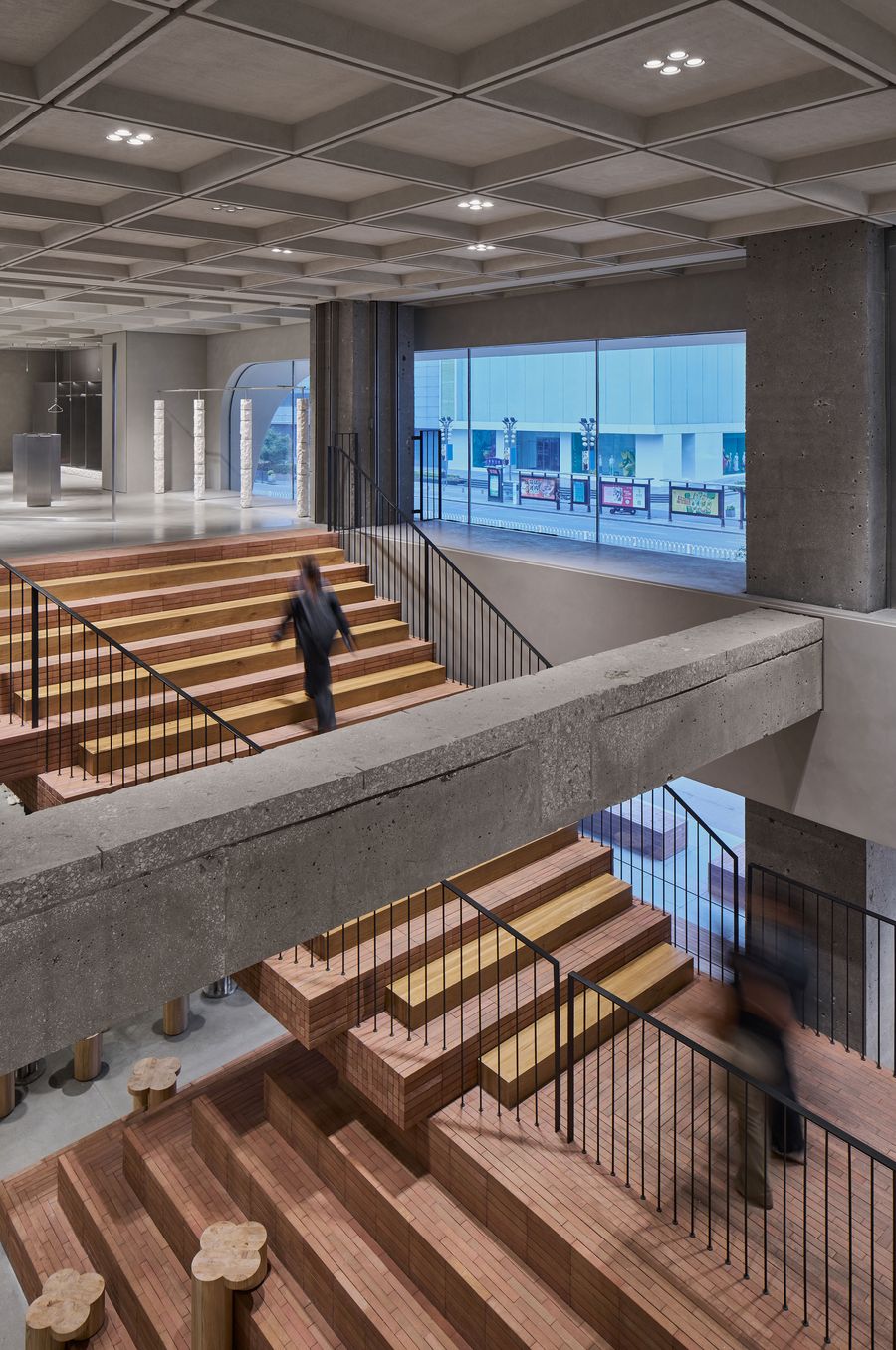 A modern interior with wooden stairs, concrete elements, and a person walking, highlighted by large windows and clean lines. A modern interior with wooden stairs, concrete elements, and a person walking, highlighted by large windows and clean lines.