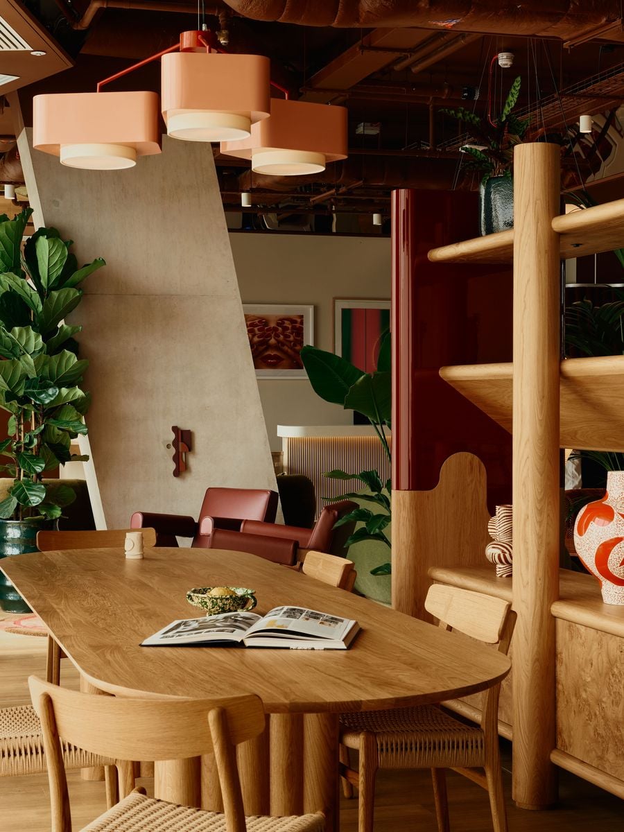 The co-working area centres on a large oak table surrounded by woven timber chairs, creating a calmer counterpoint to the lounge’s richer colours. Bespoke shelving, glossy burgundy lacquer, burl-like timber grain and oversized pendant lighting maintain Holloway Li’s layered material language within the more functional setting. The co-working area centres on a large oak table surrounded by woven timber chairs, creating a calmer counterpoint to the lounge’s richer colours. Bespoke shelving, glossy burgundy lacquer, burl-like timber grain and oversized pendant lighting maintain Holloway Li’s layered material language within the more functional setting.