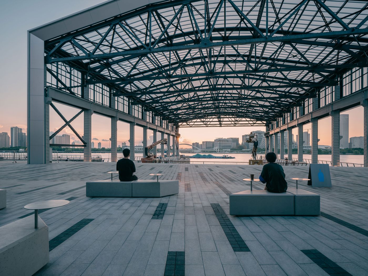 Under a vast steel canopy on the Huangpu River, minimalist concrete benches and café tables echo the architecture’s industrial legacy, offering contemplative seating with panoramic views of Shanghai’s skyline.
