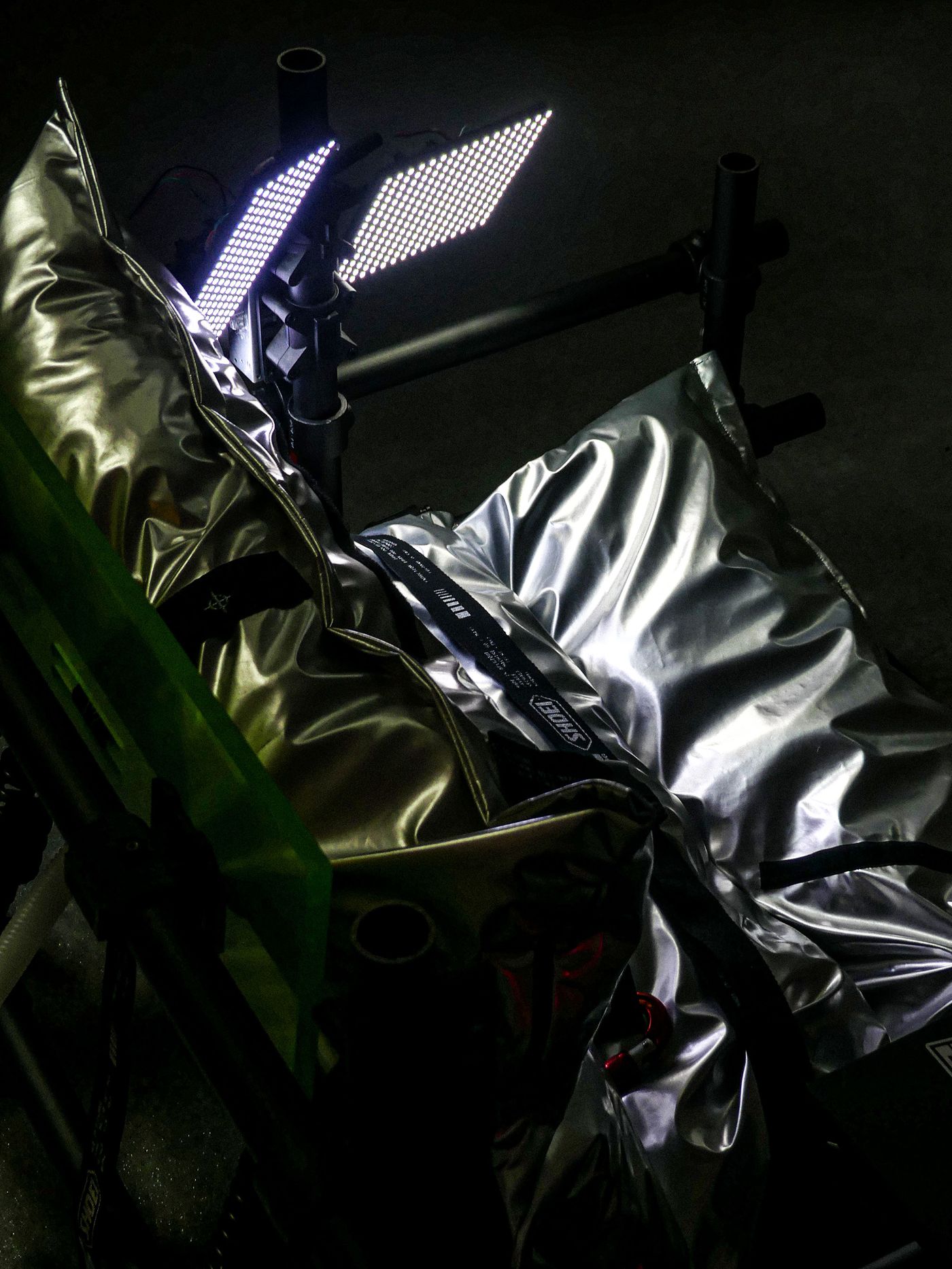 A close-up of metallic silver insulation bags on a support frame, with two bright LED panels illuminating the setup.