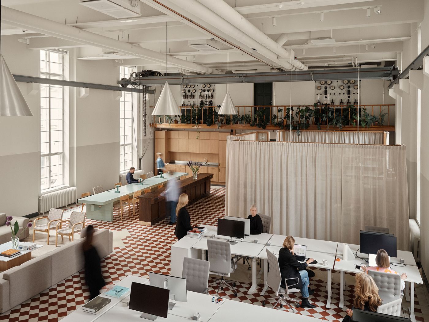 A bustling open-plan office features white desks with computer monitors and ergonomic chairs, set on a red and white checkerboard floor. In the background, sheer curtains partition a lounge area, while an elevated mezzanine overlooks the vibrant workspace. A bustling open-plan office features white desks with computer monitors and ergonomic chairs, set on a red and white checkerboard floor. In the background, sheer curtains partition a lounge area, while an elevated mezzanine overlooks the vibrant workspace.