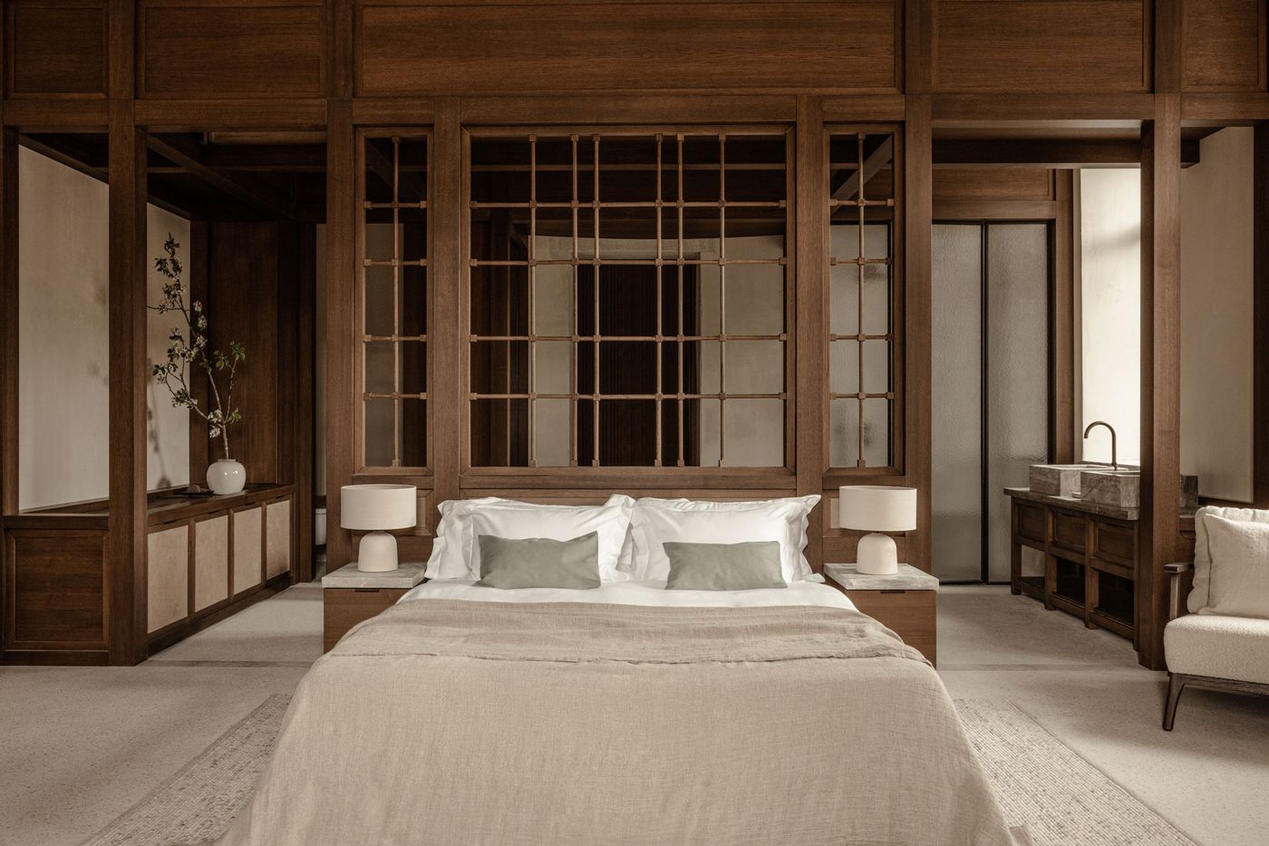 A symmetrical bedroom displays a calming Japandi aesthetic, centered around a bed with light linens and subtle green cushions. The room is enveloped by an intricate system of dark timber-framed walls and decorative screens, creating a sense of intimate enclosure while maintaining an open flow to adjacent spaces with built-in storage and a visible bathroom area. A symmetrical bedroom displays a calming Japandi aesthetic, centered around a bed with light linens and subtle green cushions. The room is enveloped by an intricate system of dark timber-framed walls and decorative screens, creating a sense of intimate enclosure while maintaining an open flow to adjacent spaces with built-in storage and a visible bathroom area.