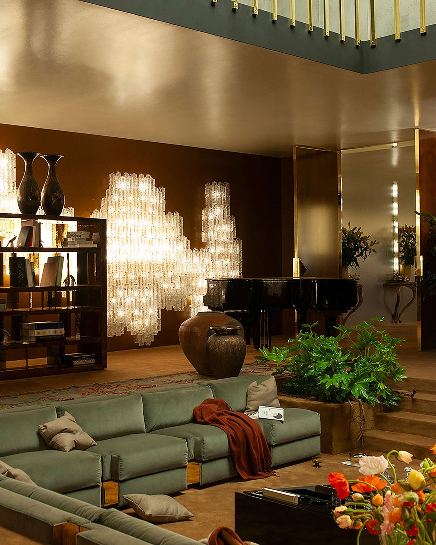 Luxurious living room featuring a grand piano, plush green sofa, elegant lighting, and lush greenery, creating a warm and inviting atmosphere.
