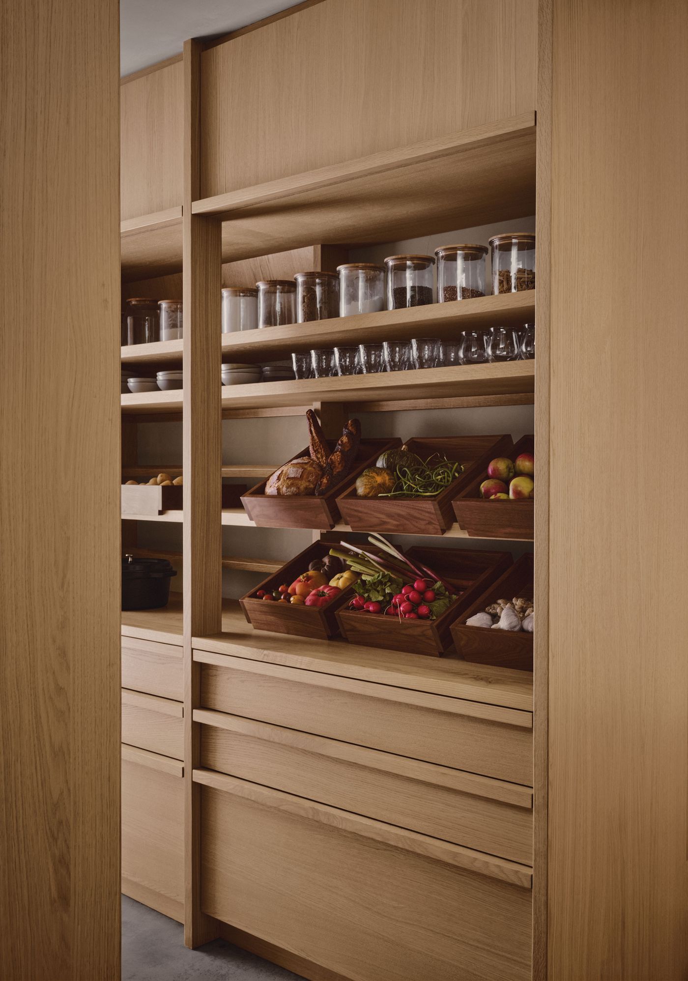 A modern wooden pantry featuring neatly organized jars, glassware, and wooden baskets filled with fresh produce and baked goods. A modern wooden pantry featuring neatly organized jars, glassware, and wooden baskets filled with fresh produce and baked goods.