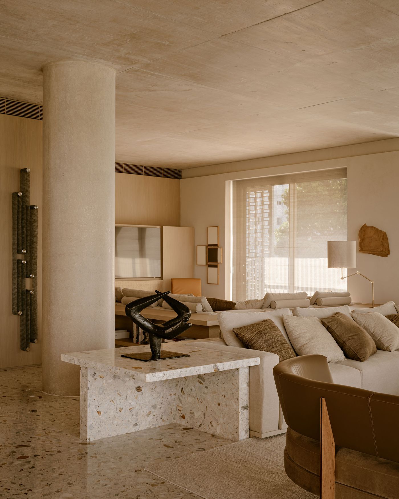A modern living room featuring a terrazzo coffee table, a clay sculpture, and a comfortable sofa with beige and brown cushions. A modern living room featuring a terrazzo coffee table, a clay sculpture, and a comfortable sofa with beige and brown cushions.