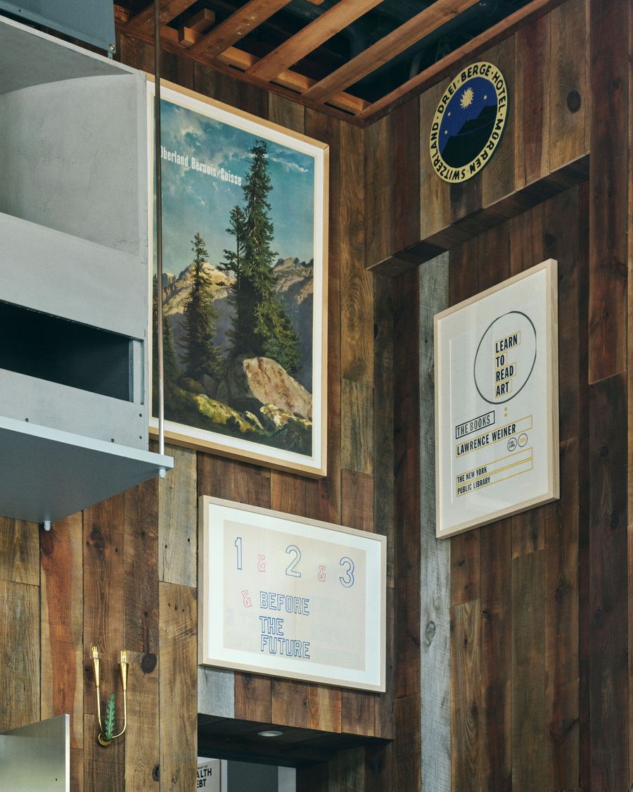 A cozy wooden wall adorned with framed vintage mountain artwork and modern graphic prints, including a poster about learning art.
