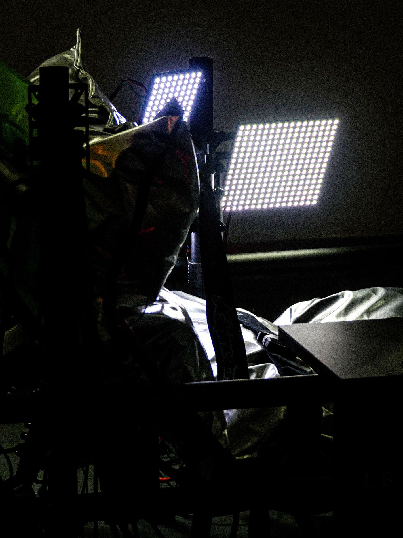 Illuminated LED panels shine against a backdrop of metallic fabric and equipment, creating a dramatic contrast in a dimly lit space.