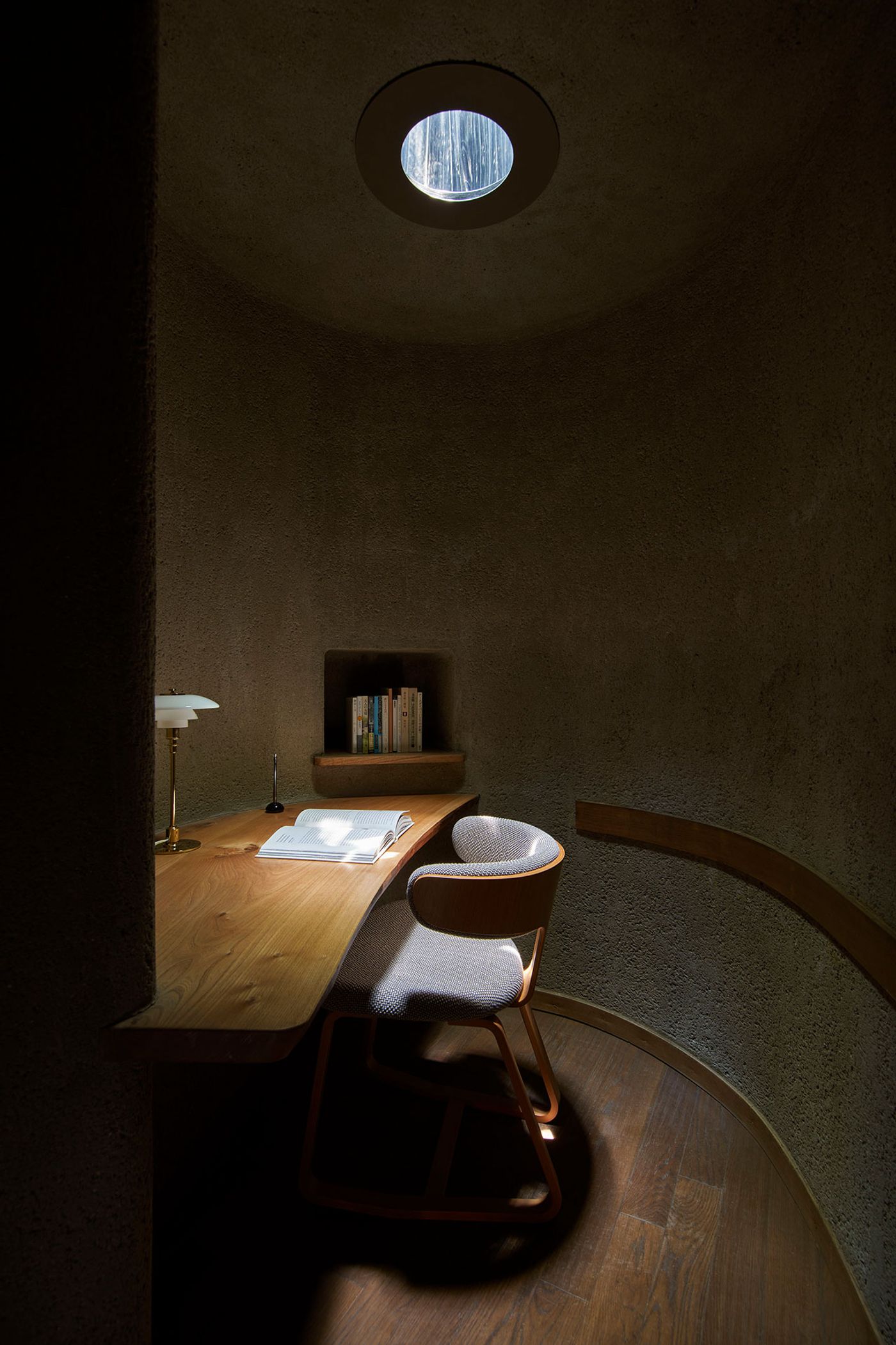 A cozy, dimly lit workspace features a wooden desk with an open book, a lamp, and a chair, illuminated by a circular skylight above. A cozy, dimly lit workspace features a wooden desk with an open book, a lamp, and a chair, illuminated by a circular skylight above.