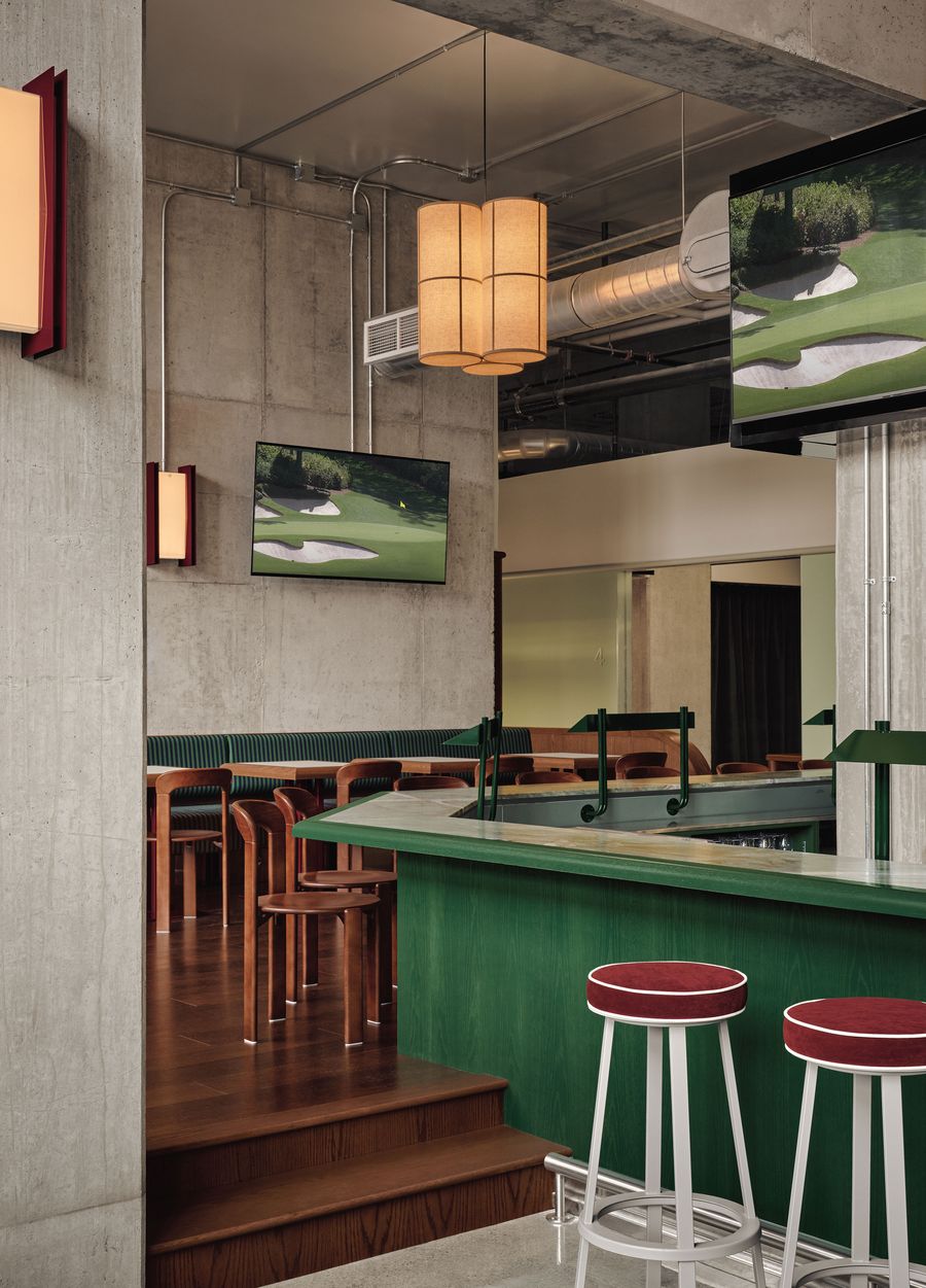 Modern bar interior with green accents, wooden stools, and TVs showing golf, highlighting a stylish, relaxed atmosphere. Modern bar interior with green accents, wooden stools, and TVs showing golf, highlighting a stylish, relaxed atmosphere.