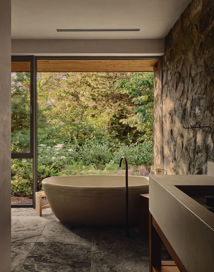 Modern bathroom with a freestanding tub, large window overlooking lush greenery, and stone accents for a serene atmosphere. Modern bathroom with a freestanding tub, large window overlooking lush greenery, and stone accents for a serene atmosphere.