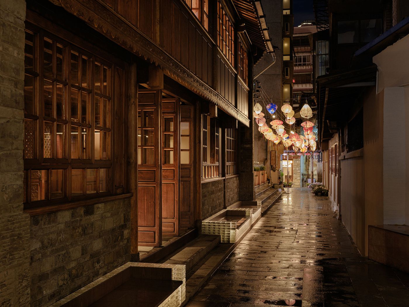 Dimly lit alleyway at night, featuring wooden buildings and colorful lanterns hanging above, reflecting off wet pavement. Dimly lit alleyway at night, featuring wooden buildings and colorful lanterns hanging above, reflecting off wet pavement.