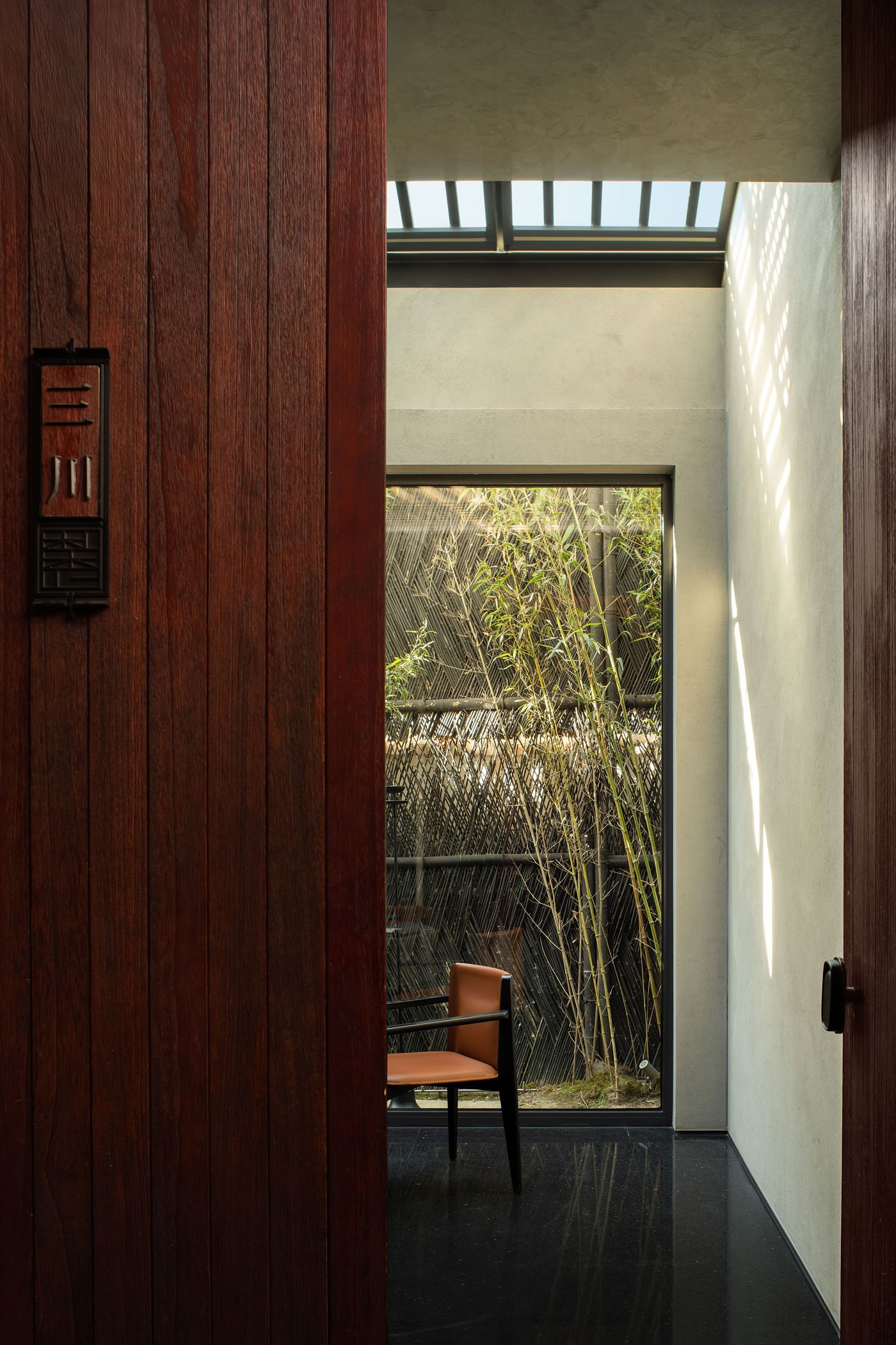 A wooden doorway frames a serene interior with a sleek chair and bamboo view, highlighting modern design and natural light. A wooden doorway frames a serene interior with a sleek chair and bamboo view, highlighting modern design and natural light.