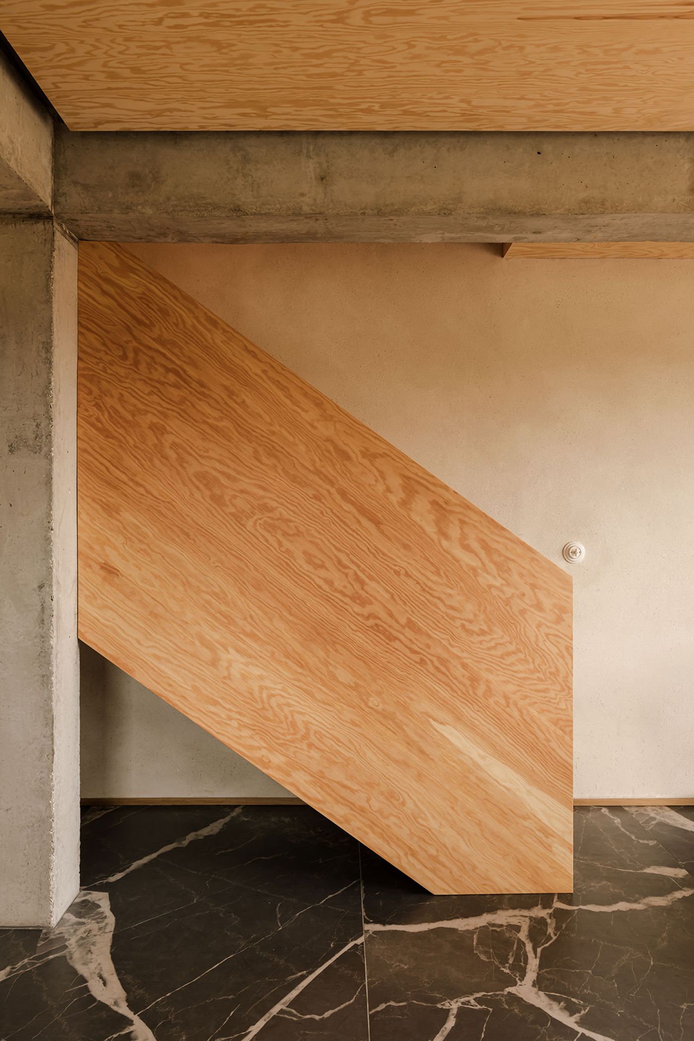 A modern wooden staircase with a sleek design, featuring a light wood finish against a concrete wall and dark marbled floor. A modern wooden staircase with a sleek design, featuring a light wood finish against a concrete wall and dark marbled floor.