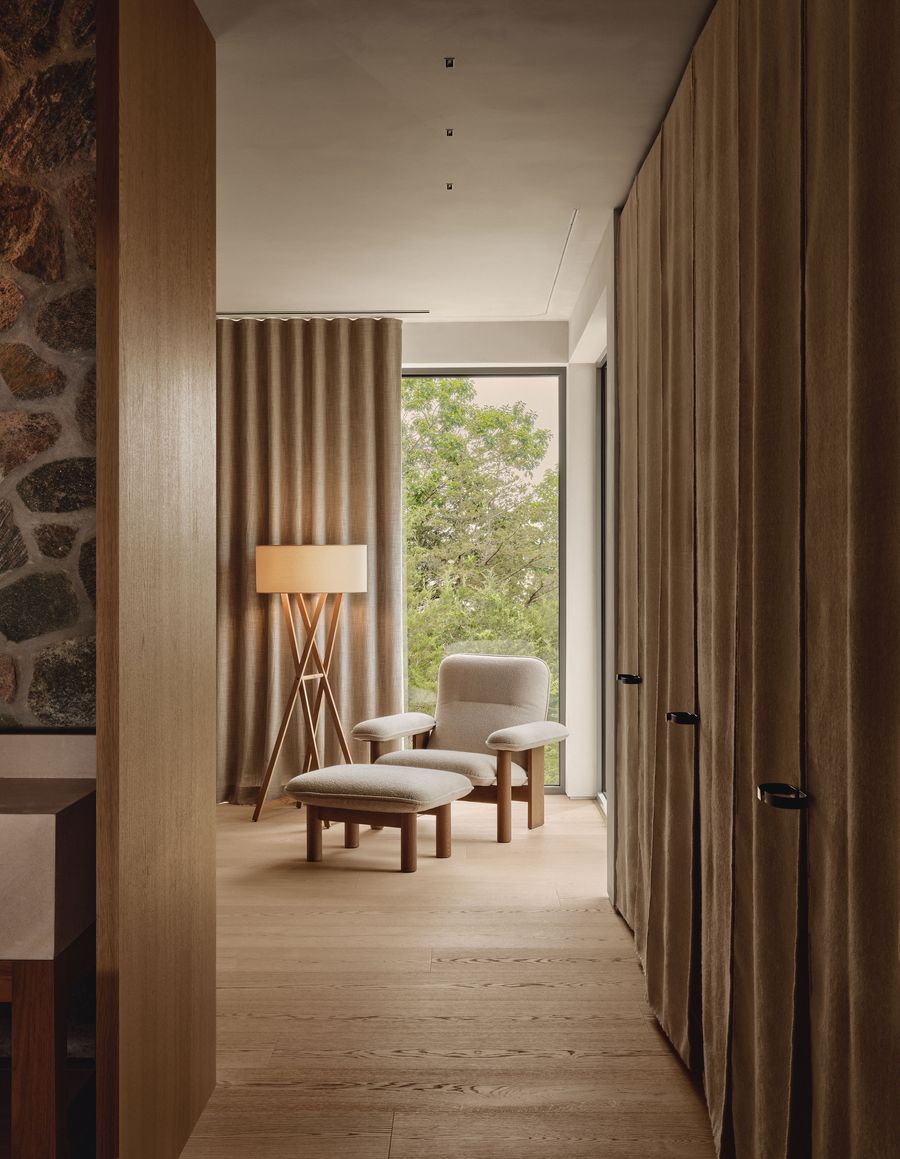 A serene interior hallway featuring wooden floors, soft curtains, a cozy seating area, and a floor lamp illuminating the space. A serene interior hallway featuring wooden floors, soft curtains, a cozy seating area, and a floor lamp illuminating the space.