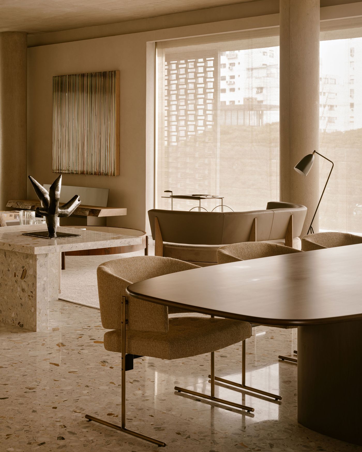 A modern, neutral-toned living space featuring sleek furniture, a sculptural centerpiece, and large windows with sheer curtains. A modern, neutral-toned living space featuring sleek furniture, a sculptural centerpiece, and large windows with sheer curtains.