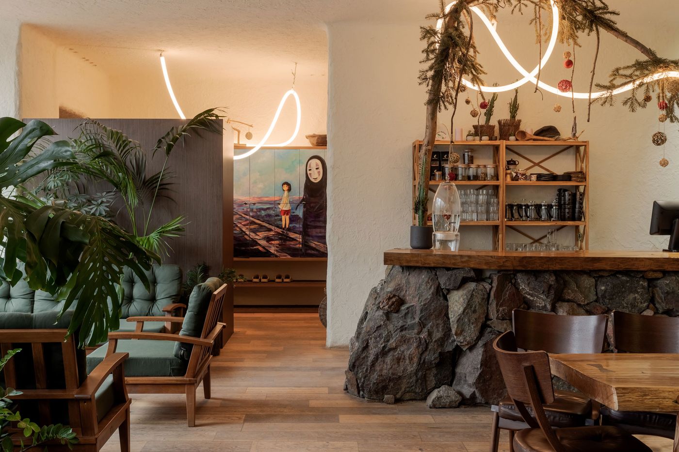Cozy café interior featuring wooden furniture, plants, and artistic décor with modern lighting and a rustic stone bar. Cozy café interior featuring wooden furniture, plants, and artistic décor with modern lighting and a rustic stone bar.