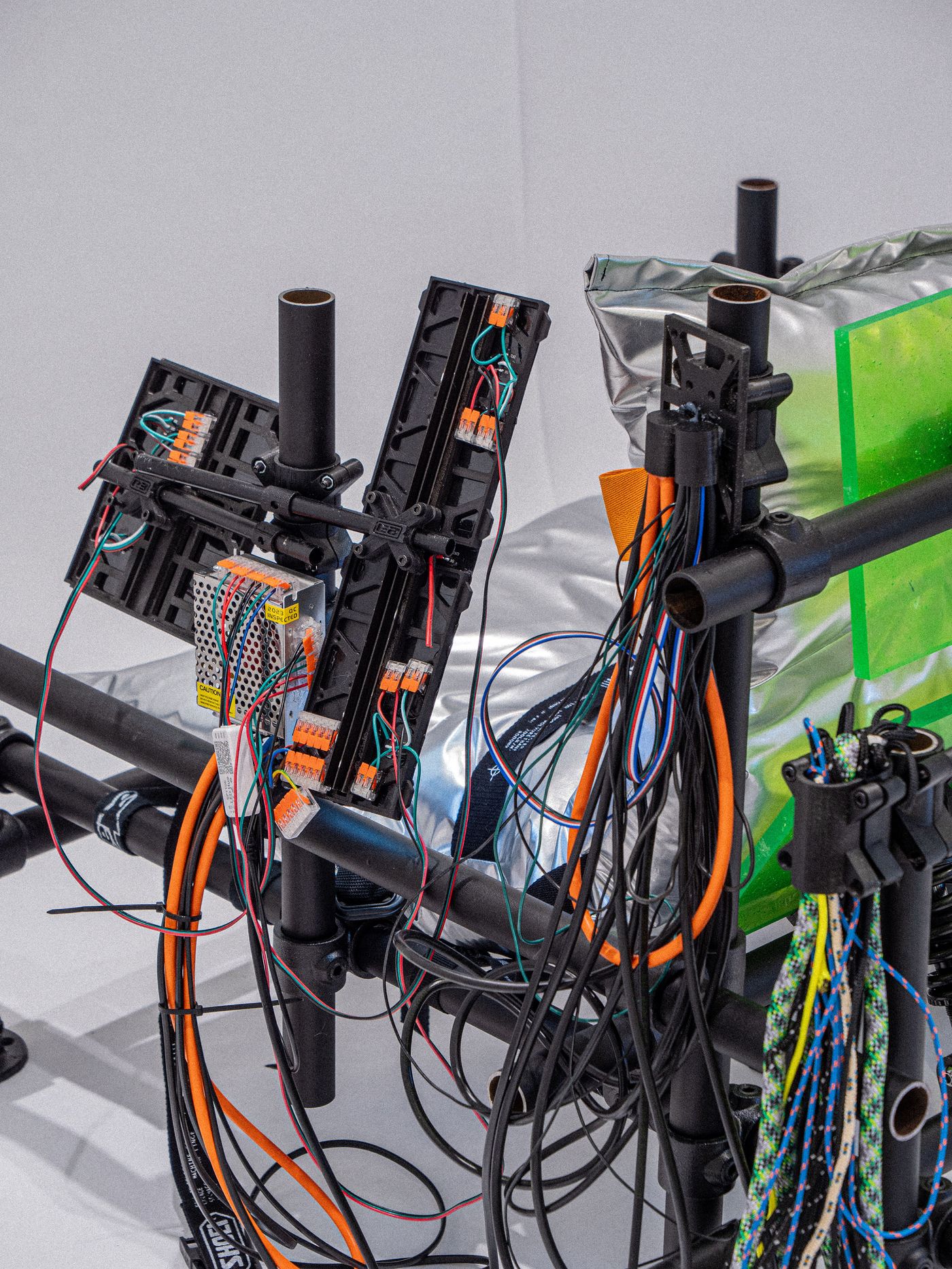 A close-up of a complex assembly of wires and electronic components attached to a frame, showcasing intricate connections and an industrial design. A close-up of a complex assembly of wires and electronic components attached to a frame, showcasing intricate connections and an industrial design.